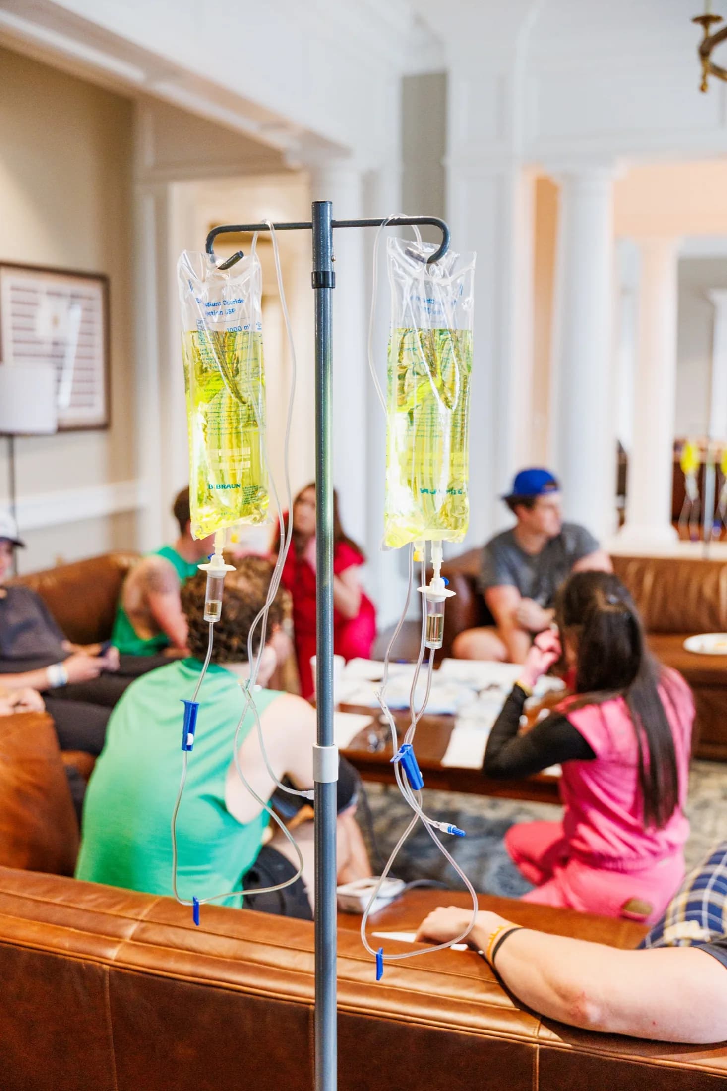 A group of friends receiving IV drips together on couches at a fraternity house