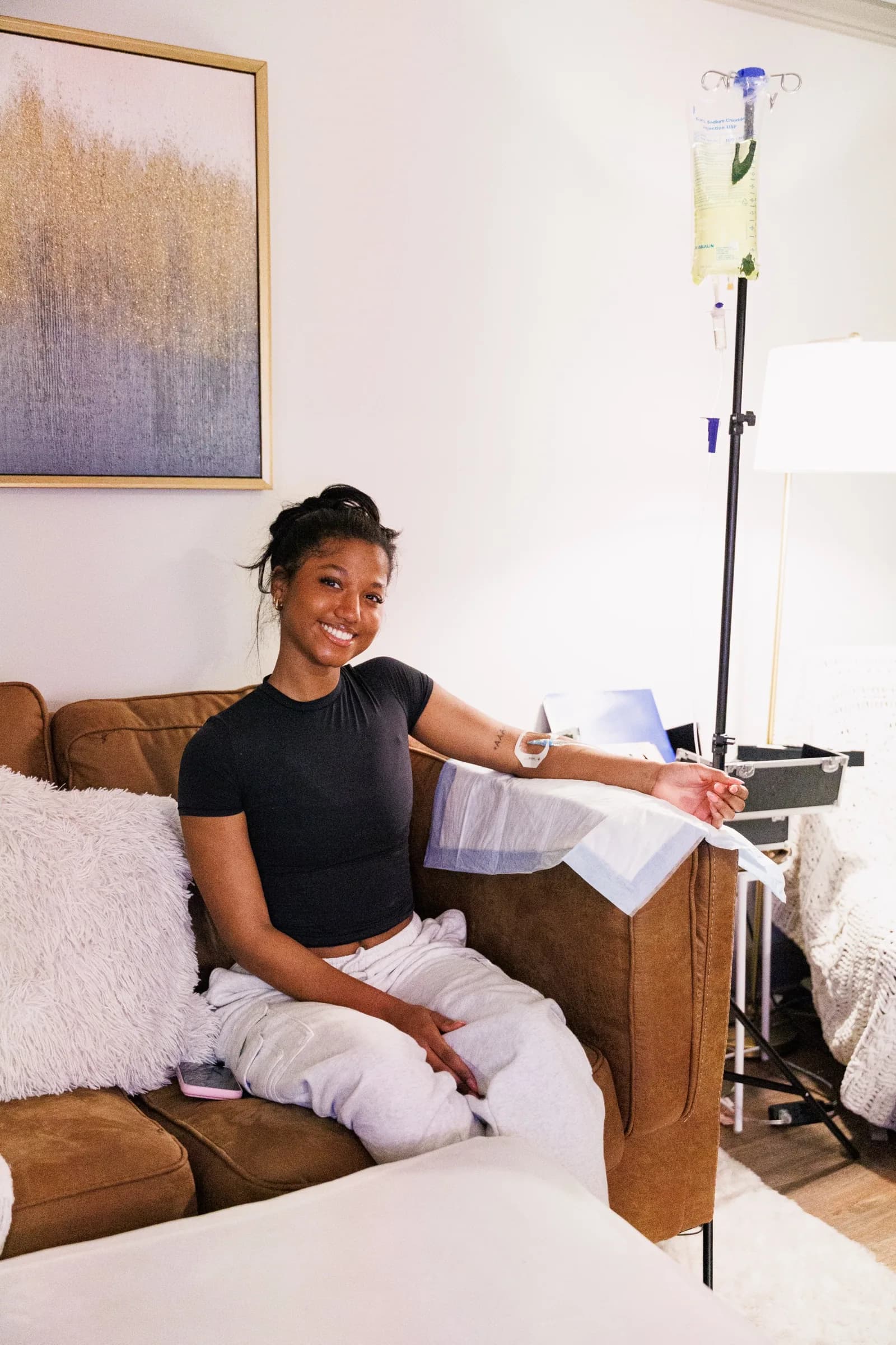 A ThrIVe client relaxing on her couch at home during an IV drip, with the IV pole beside her